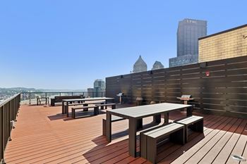 A rooftop patio with wooden flooring and furniture at LiveWell Apartments, Pittsburgh, Pennsylvania